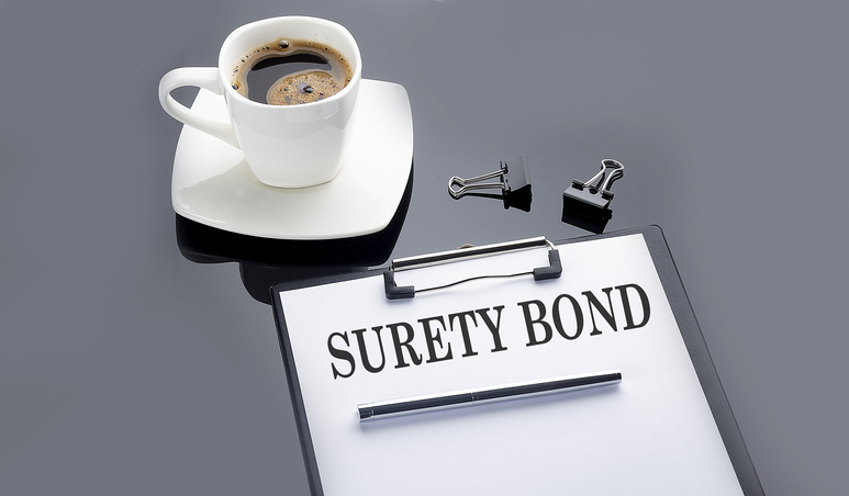 SURETY BOND text on paper sheet with coffee on the black background